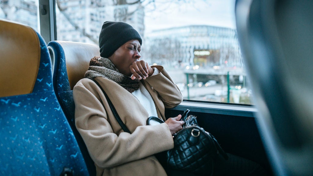 A woman yawns while riding a bus.