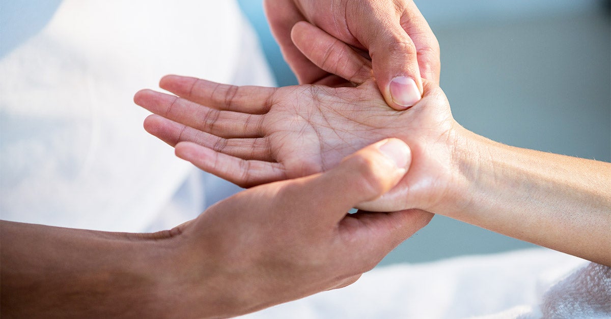 Therapist giving hand massage by pressing on the client's right palm