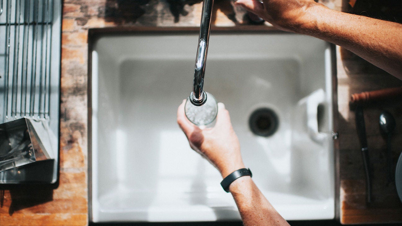 A person getting water from a faucet.