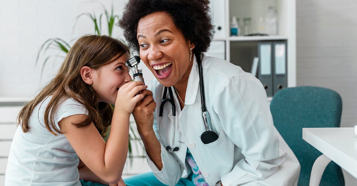Smiling female afro american doctor general practitioner talks and amuses child before medical examination 1200x628 facebook - Physician vs Doctor vs Surgeons Job
