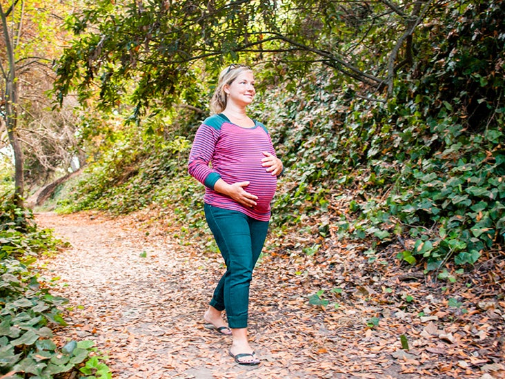 Pregnant Caucasian woman holding her stomach on forest path 732x549 thumbnail