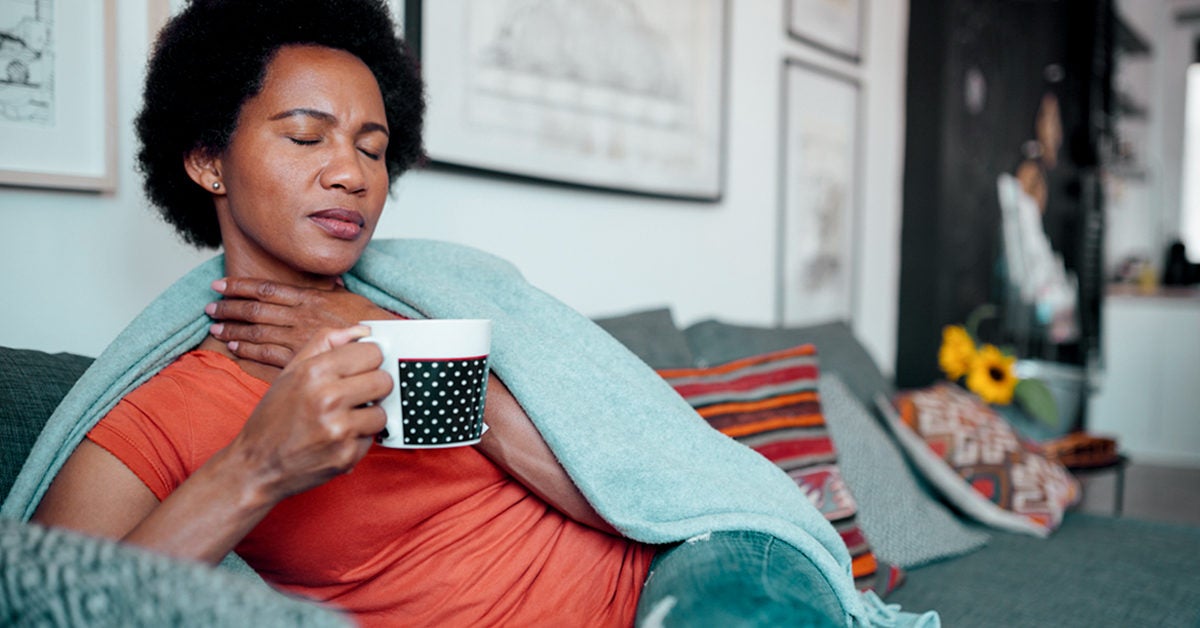 woman staying at home feeling sick having a sore throat and drinking a cup of tea 1200x628 facebook