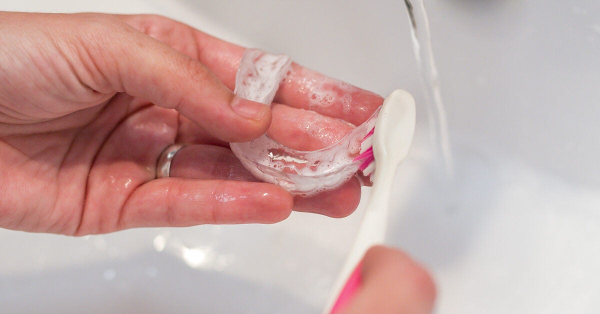 womans hands washing her invisible aligners 1200x628 facebook