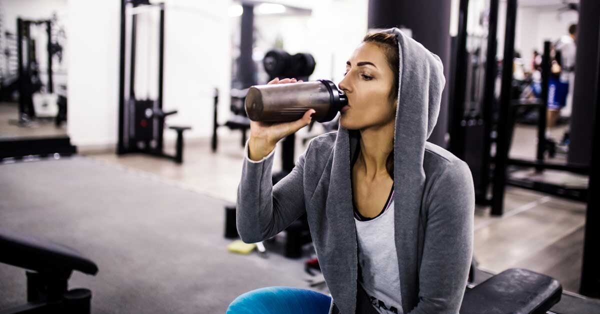 woman in gym drinking protein shake fb