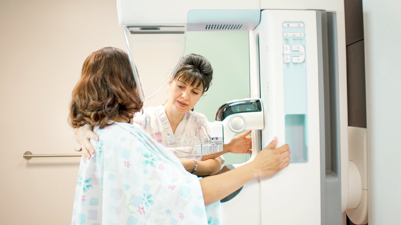 an imaging technician performing a mammogram on a woman