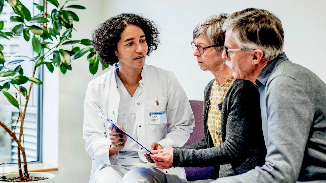 doctor showing a couple a clipboard containing test results