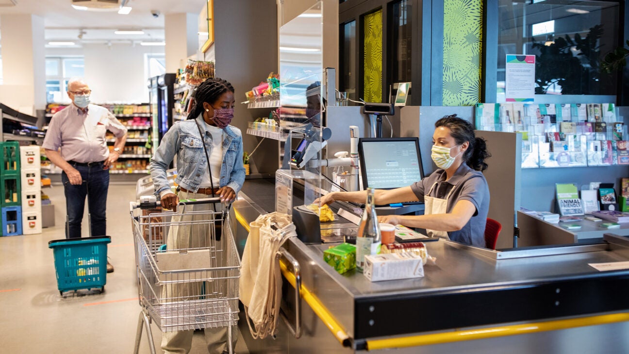 A clerk checks out a customer at a grocery store.