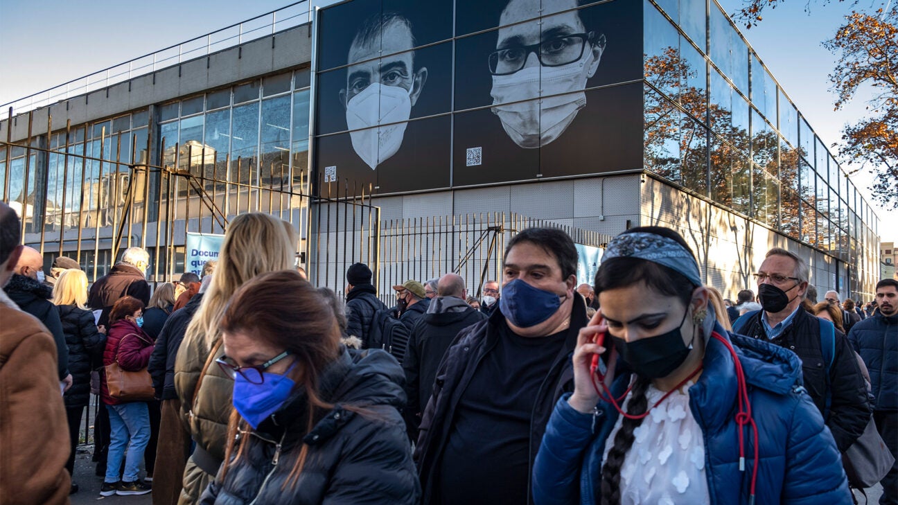 People wearing face masks wait in a crowd. 