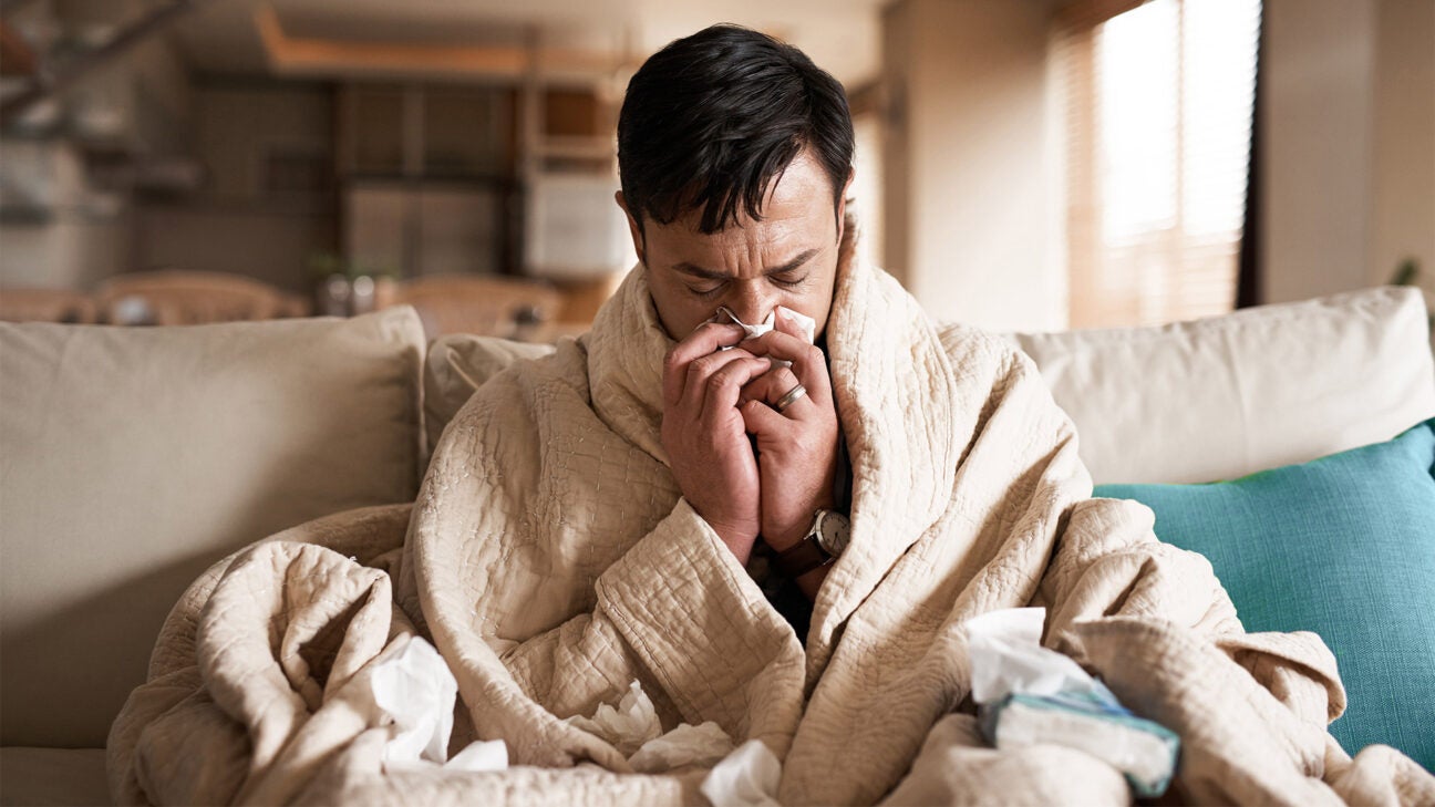 Man in his bathrobe blows his nose.