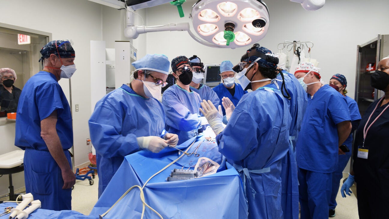 Surgeons and other medical staff are seen performing open heart surgery.