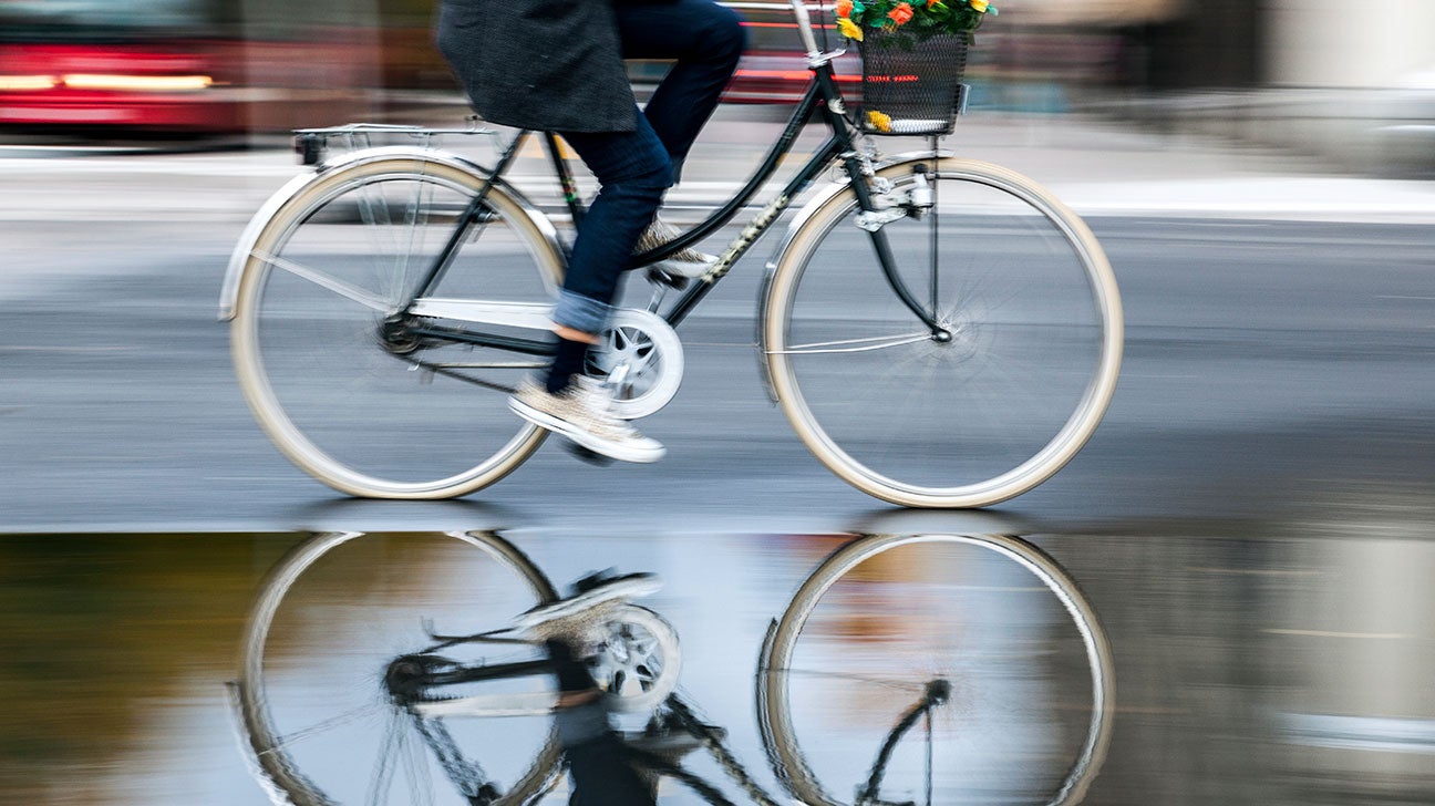 A young adult pedals a bicycle on a rain-soaked street