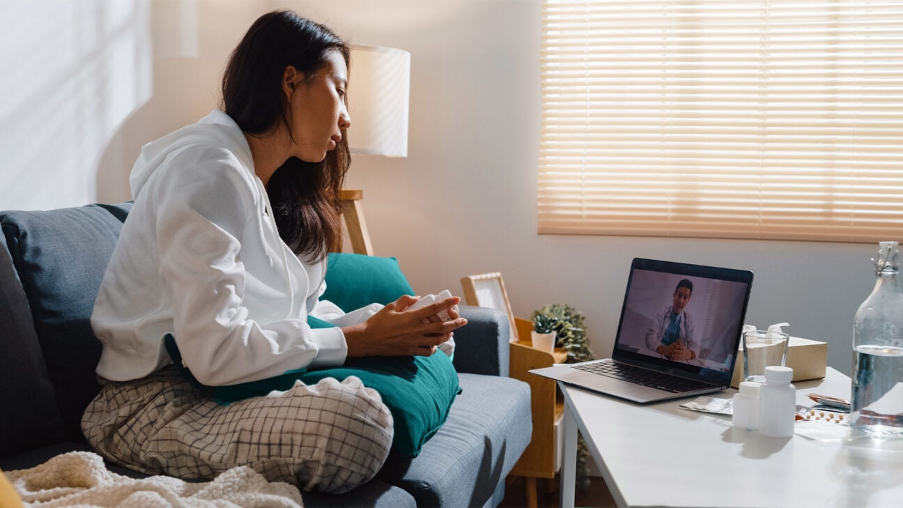 A woman talks to a physician via telehealth.