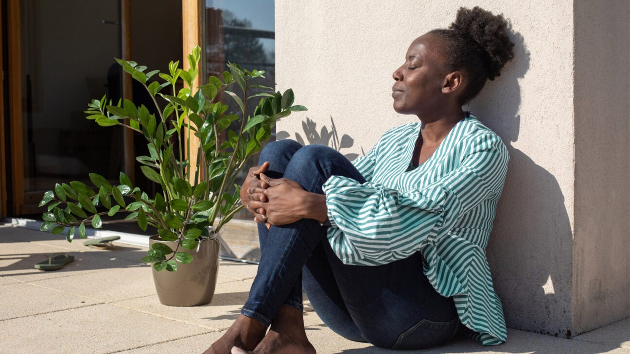 A woman sitting outside in the sun practices relaxed breathing