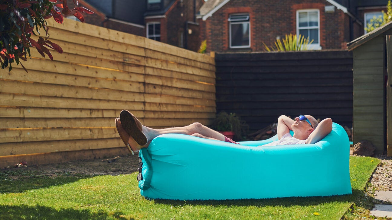 A man absorbs some sun while lounging in an inflatable chair in his back yard