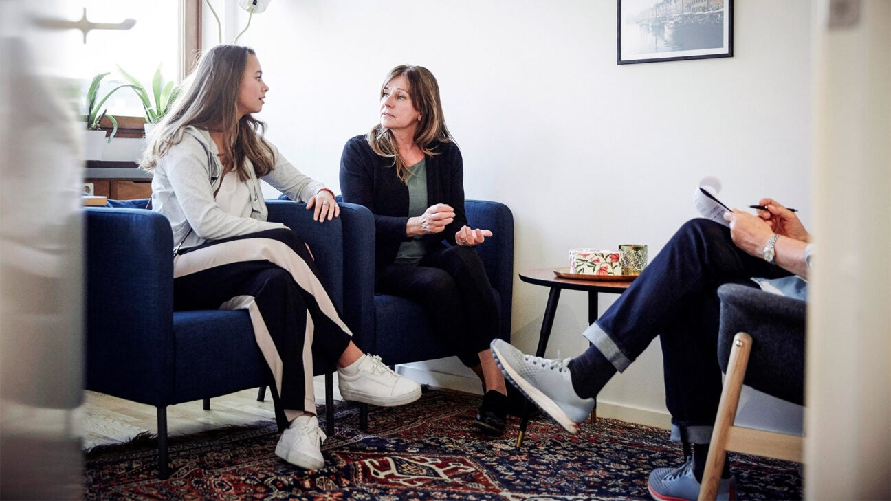 A mother and teen daughter talk with a medical professional