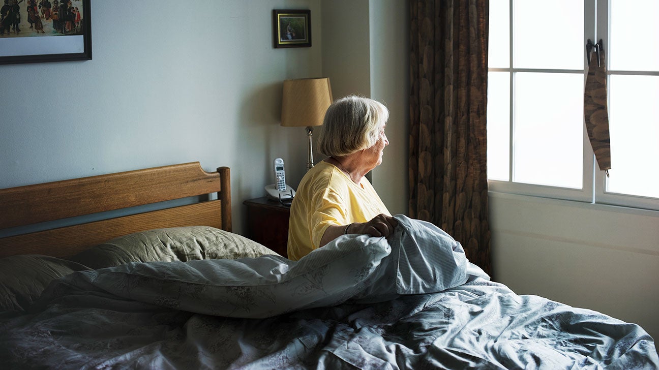 An older woman waking up in bed.