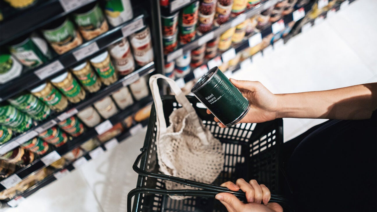 A woman checks the nutrition label on a can of baked beans at the grocery store