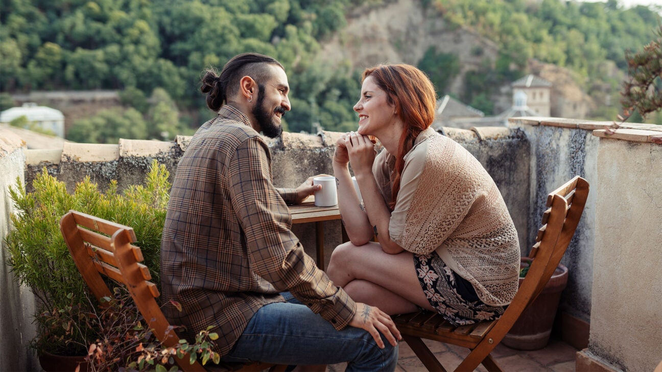 A couple drinking coffee outside.