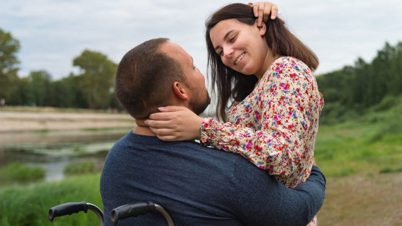 A man and a woman embrace in a field outdoors