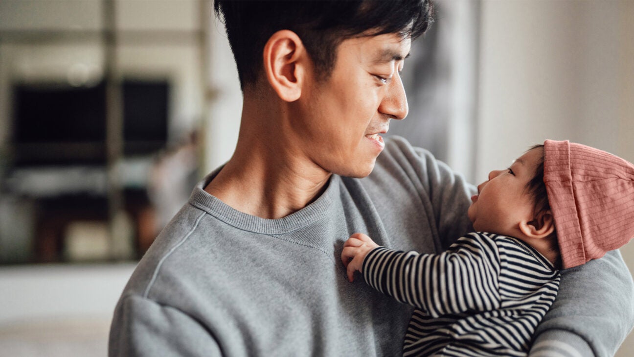 A father smiles while holding an infant in his arms