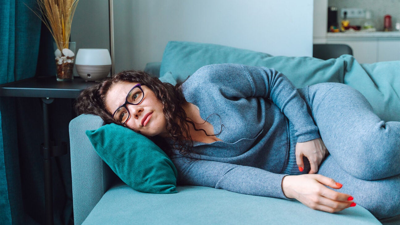 A woman stares into space while resting on a couch