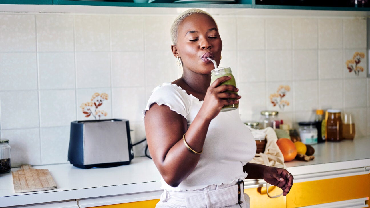 Female in a kitchen drinking a green smoothie