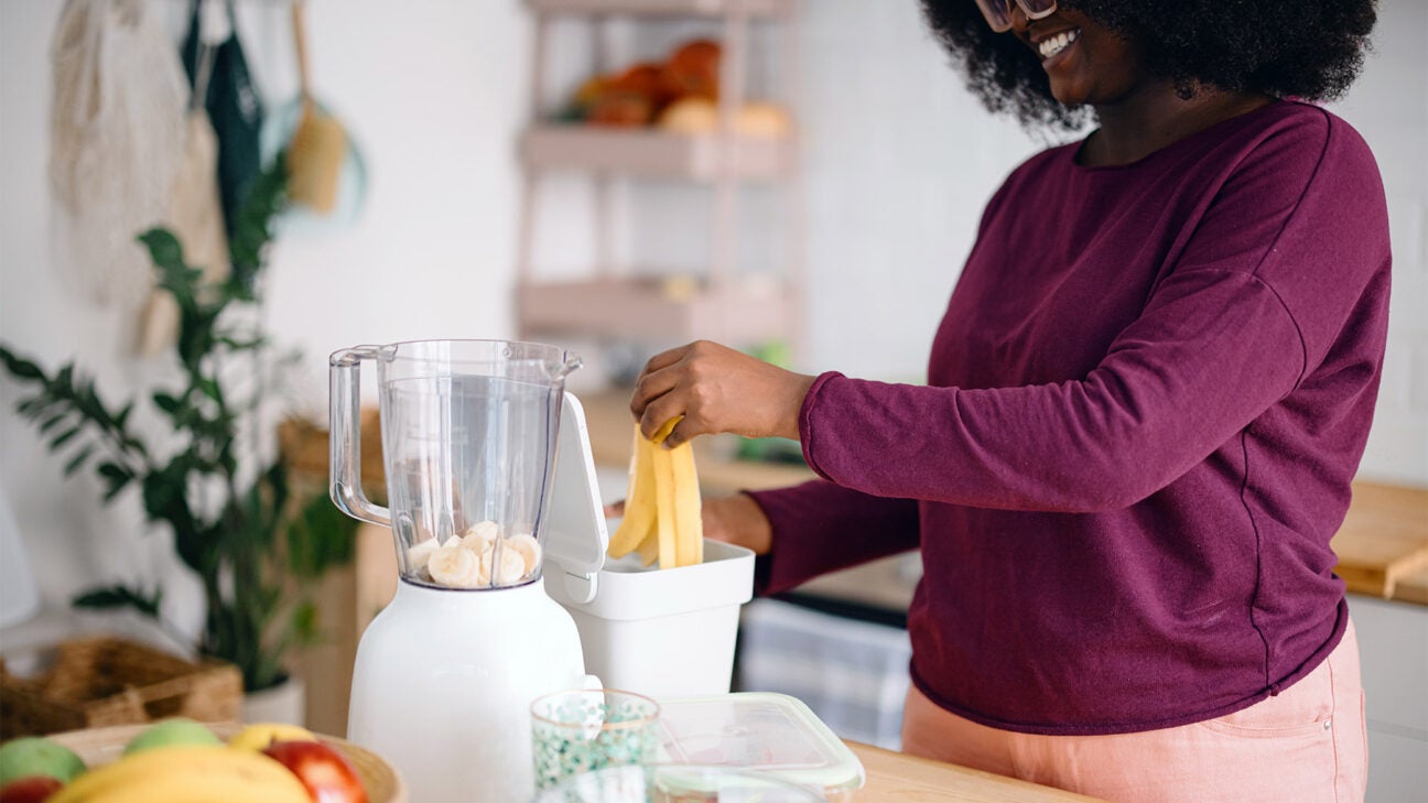 A woman prepares a smoothie with fruit in her kitchen