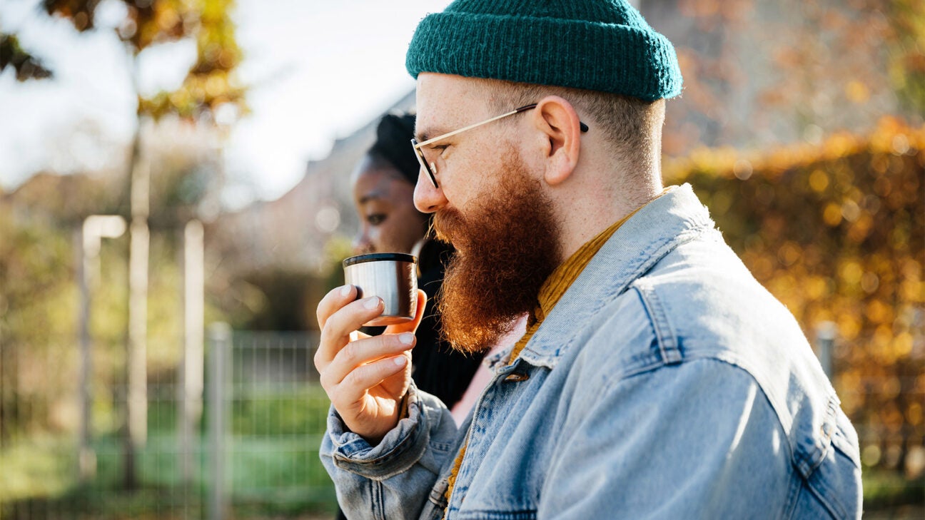 A man drinking a beverage outdoors.