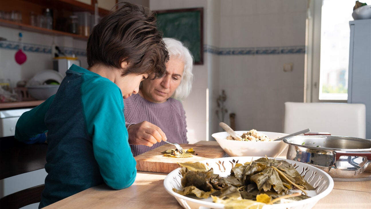 An older female eats Mediterranean style food in the kitchen with her grandchild