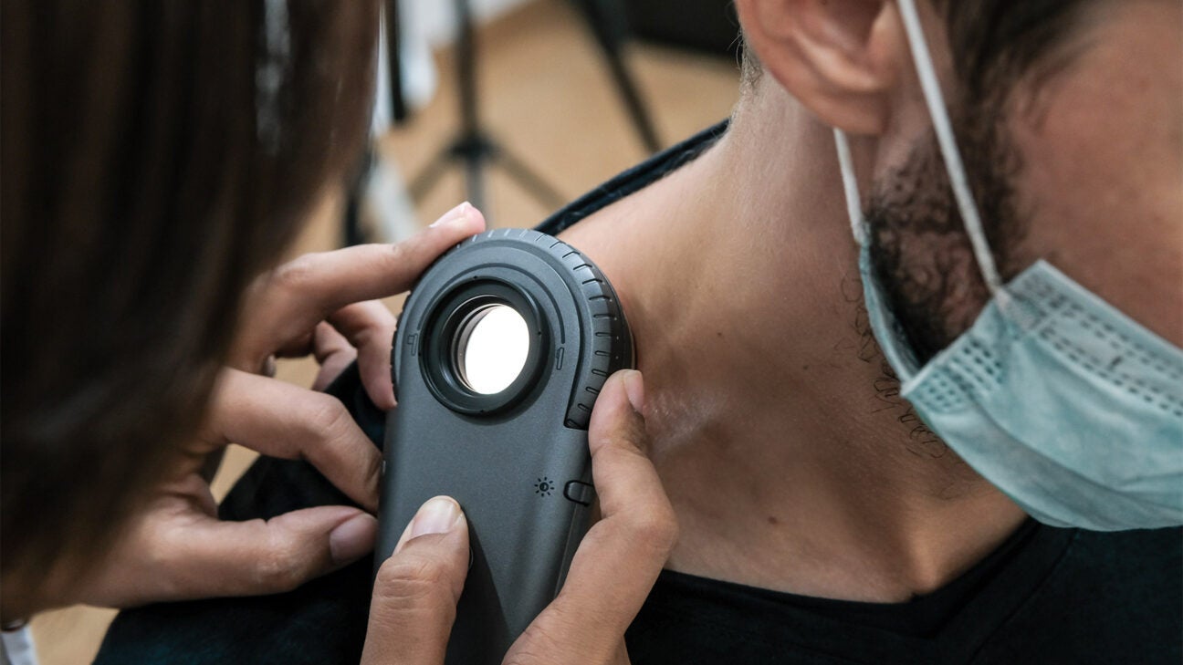 A medical professional checks the skin on a man's neck