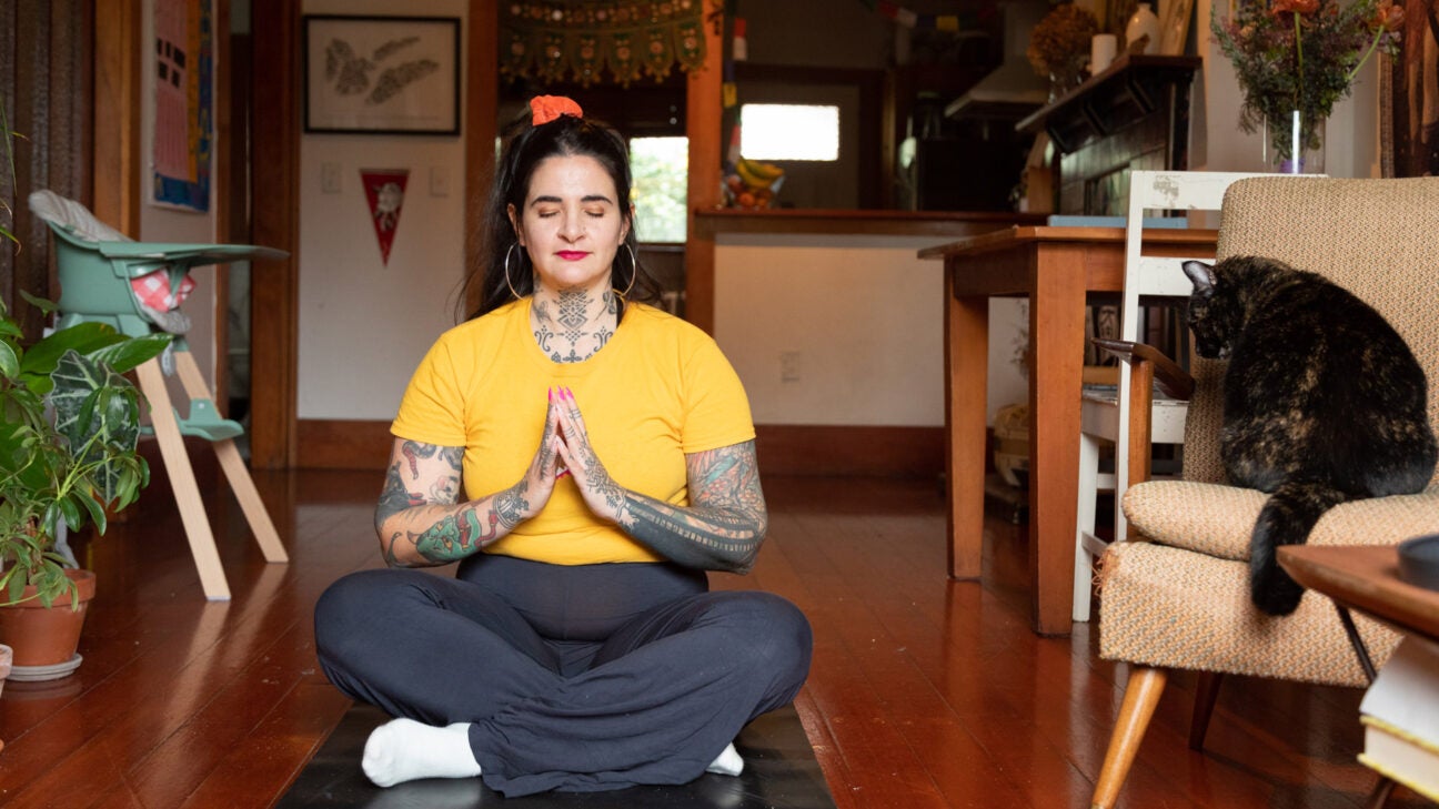 Tattooed woman practicing mindfulness at home with a cat