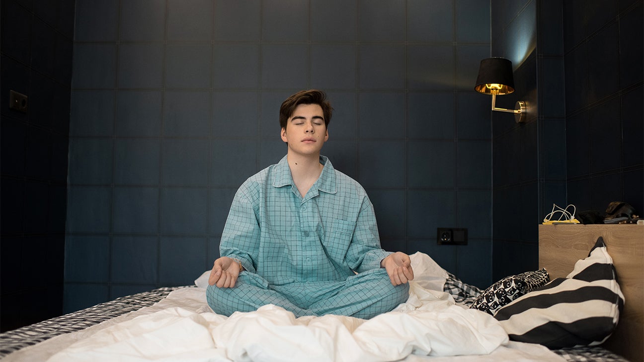 teenage boy meditating on bed