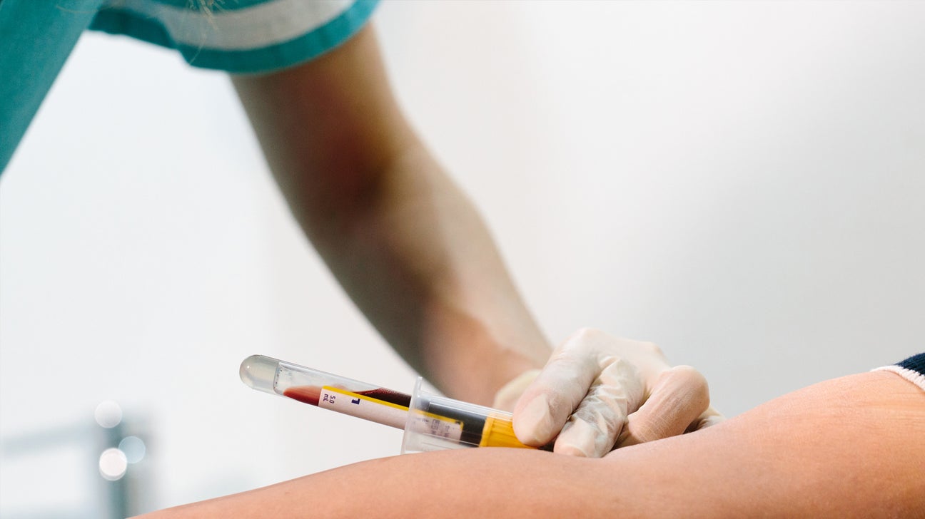 A technician takes a blood sample from a person's arm