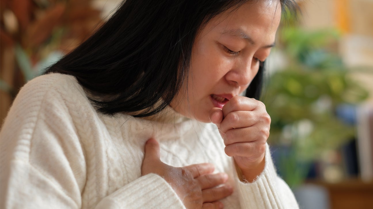 A woman coughs while holding her chest