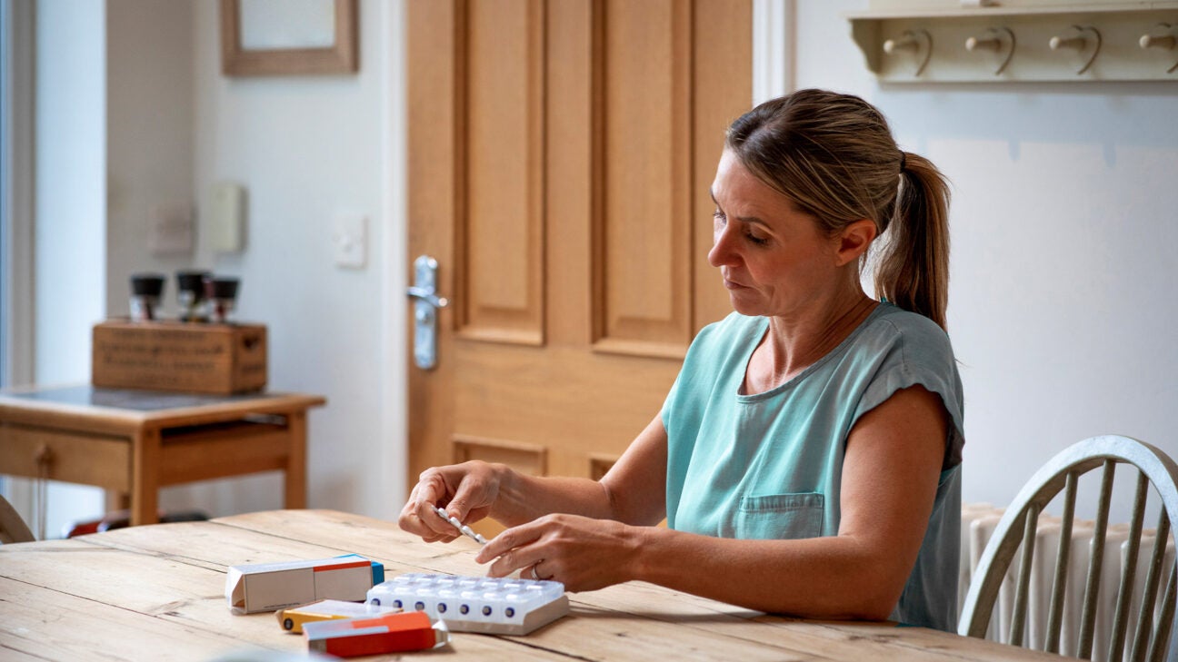 Woman puts pills into pillbox.