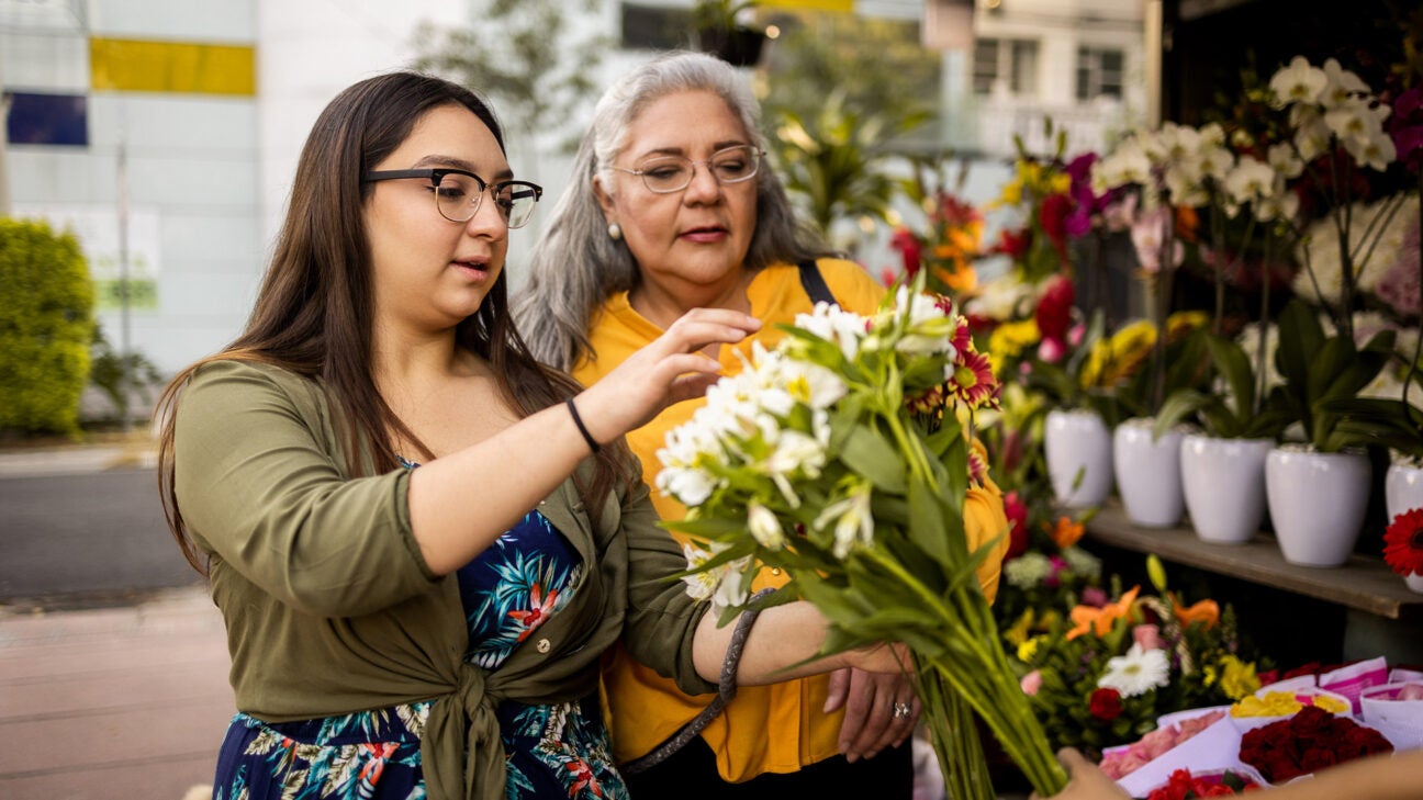 Two women look at a bouquet of flowers.