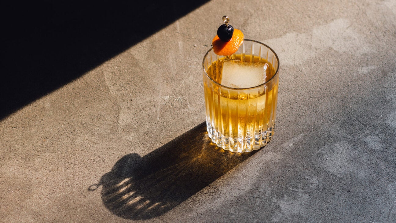 A mixed drink with an ice cube sits on a table