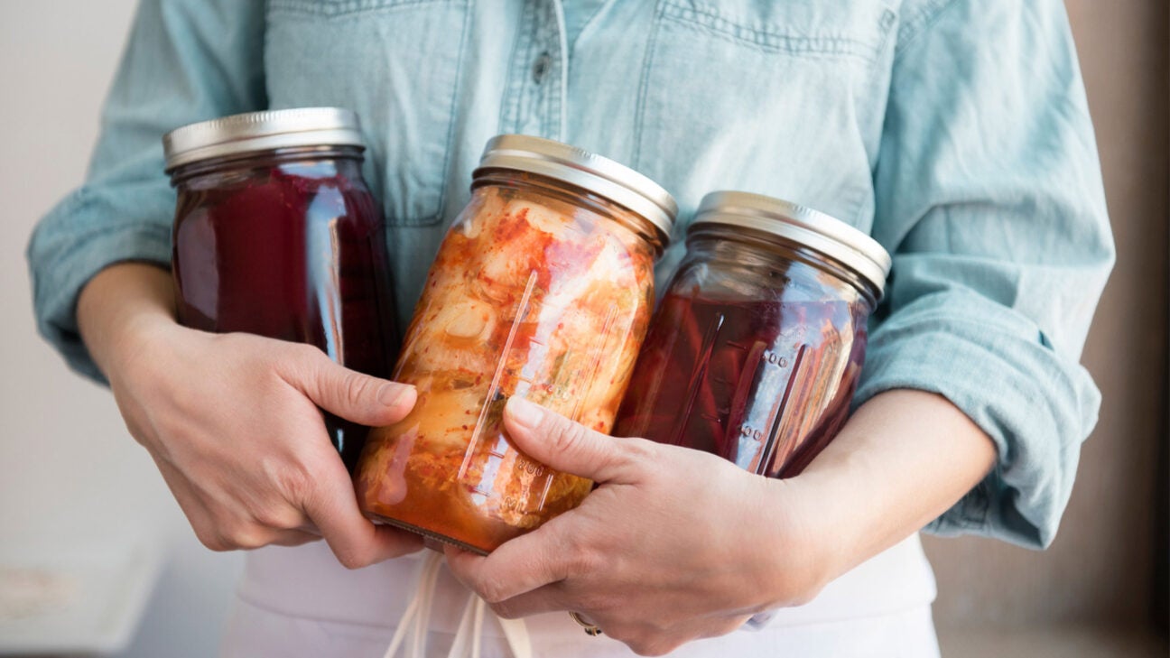 A woman holds three jars of fermented foods