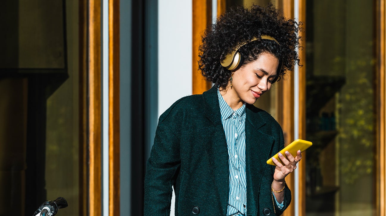 A young woman smiles while listening to music on her mobile phone