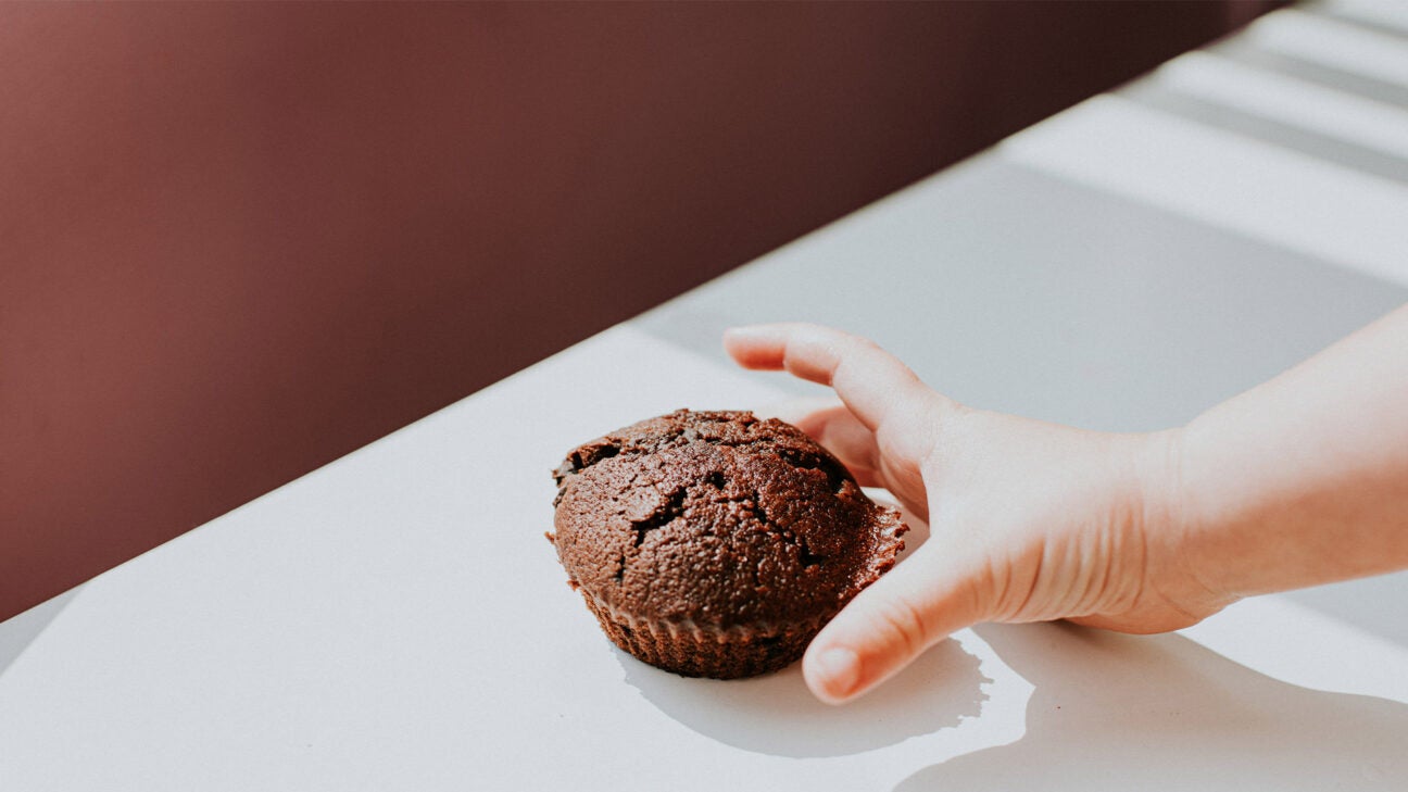 Close up image of a child's hand reaching for a brownie dessert