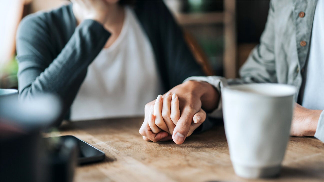 A couple holds hands on a table