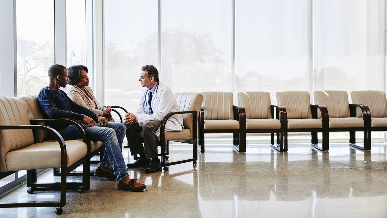 A man and woman talk with a doctor in a medical facility lobby