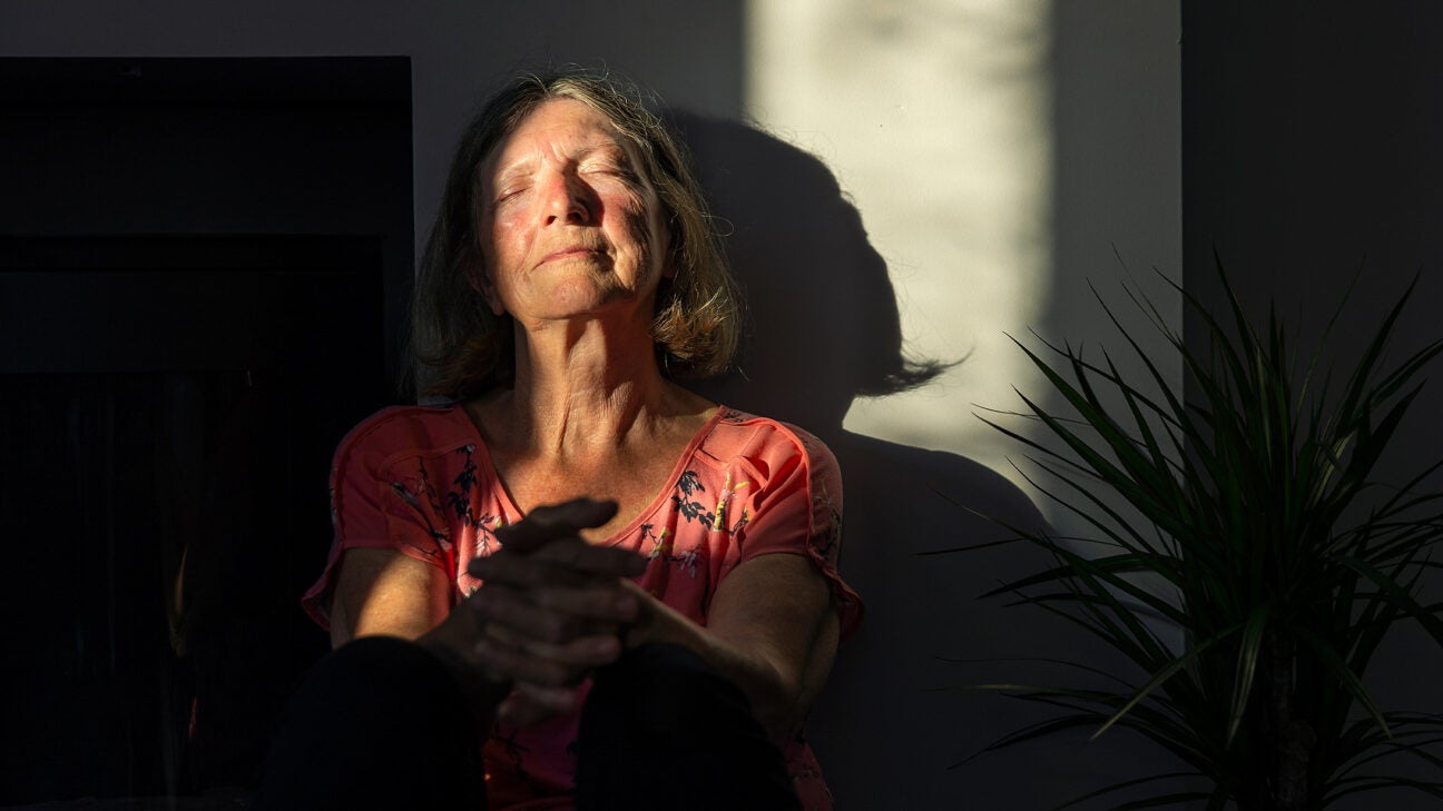 An older woman relaxes with the sun on her face