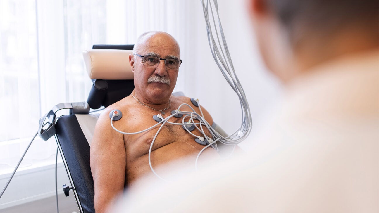 A medical professional performs an EKG on an older man