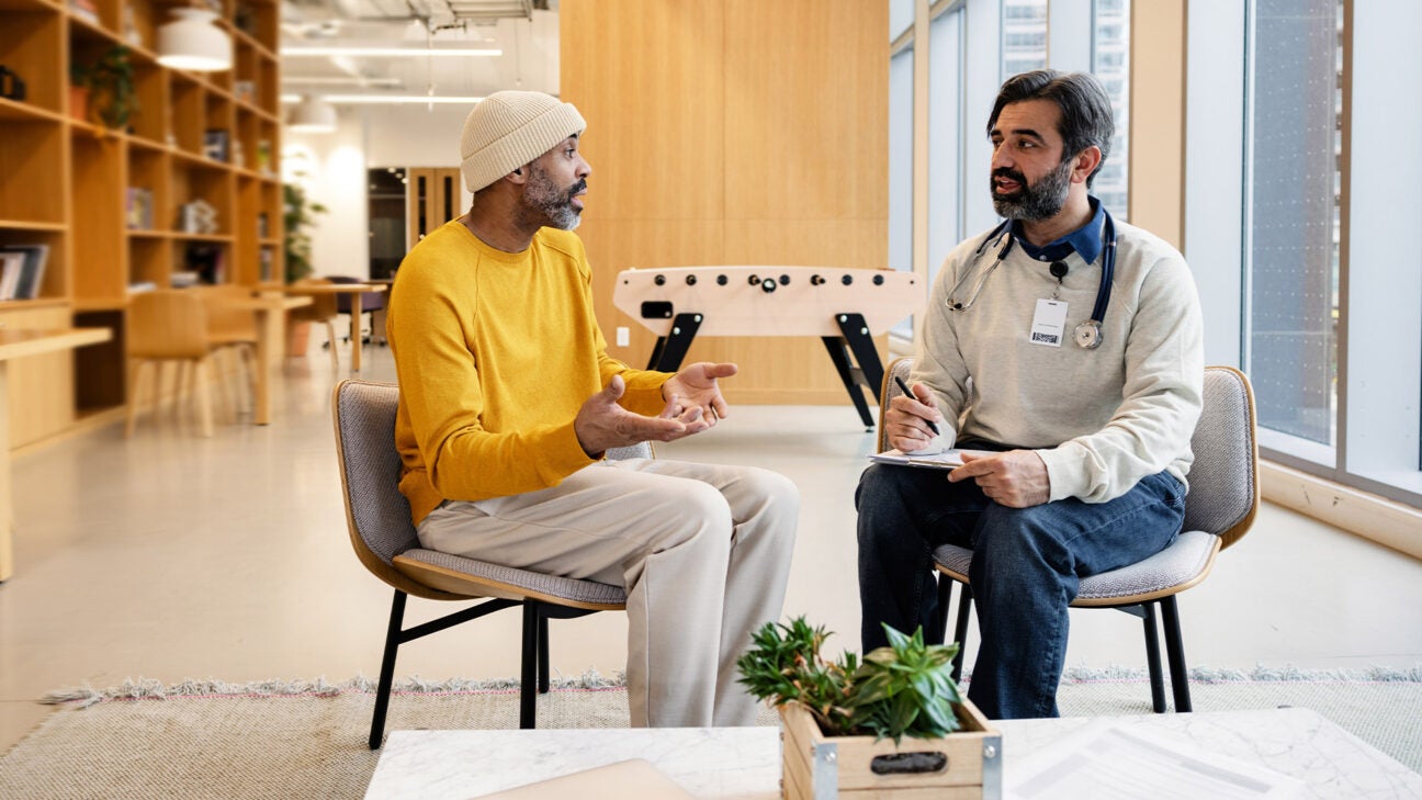 A physician talks to a patient, while seated.