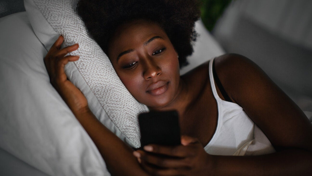 A woman looks at her phone in bed.