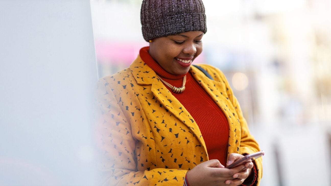 A smiling woman looking at a phone.