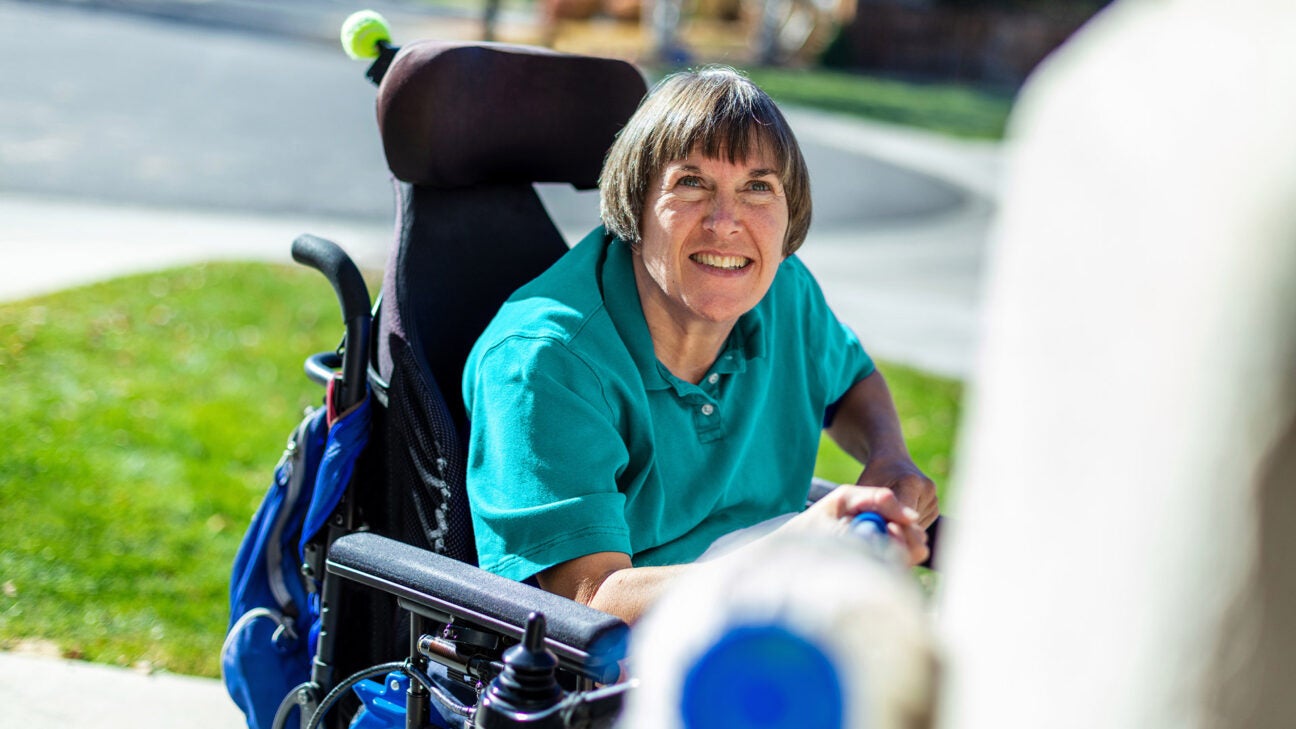 A woman in a wheelchair is seen smiling.