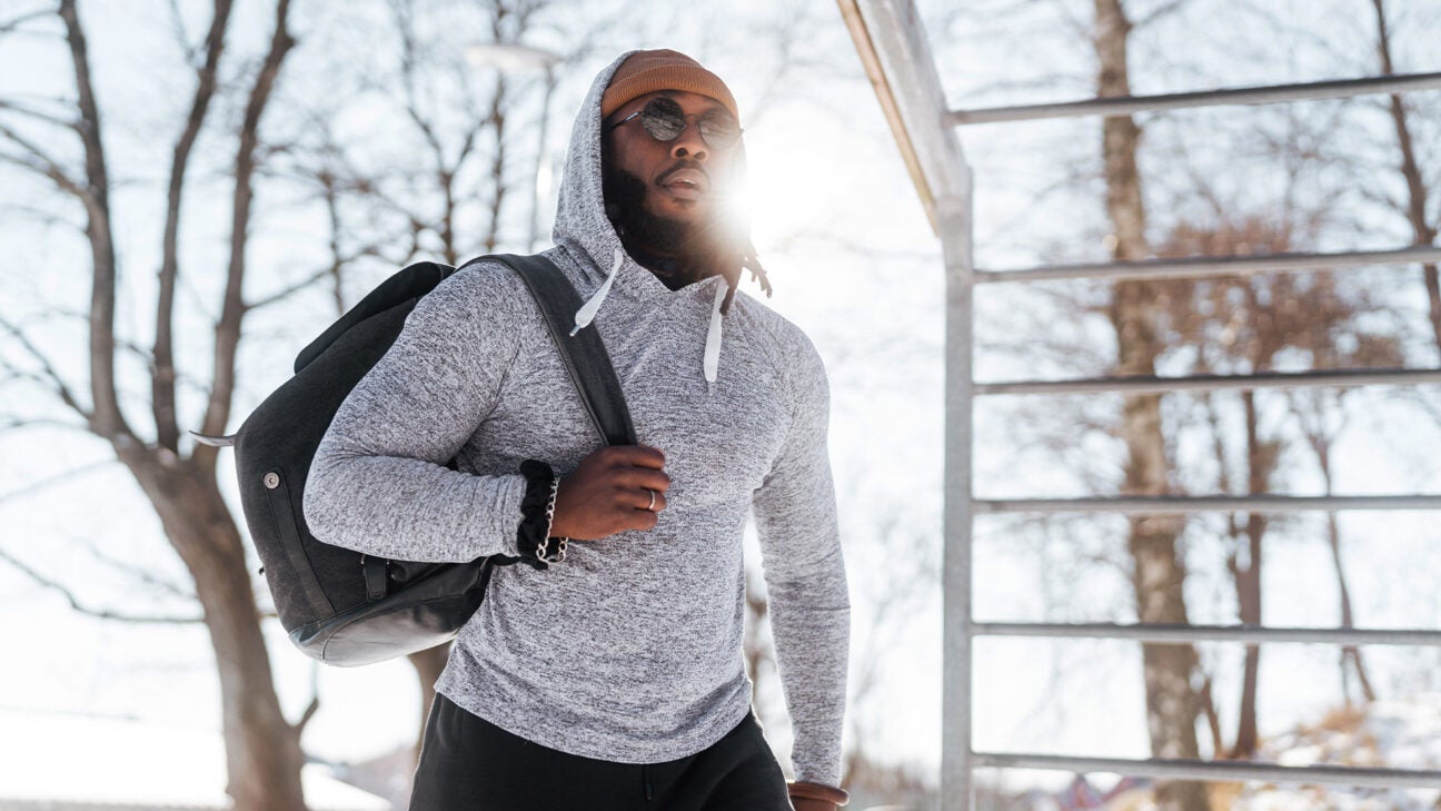 A man carrying a backpack walks outside.