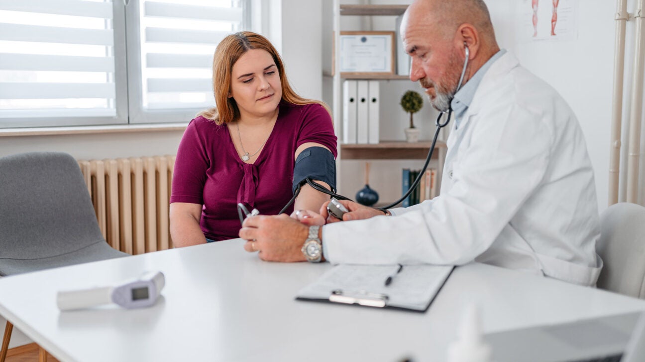 A physician checks a woman's blood pressure.